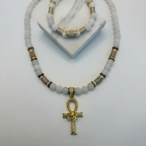 White beaded necklace with gold ankh pendant.
