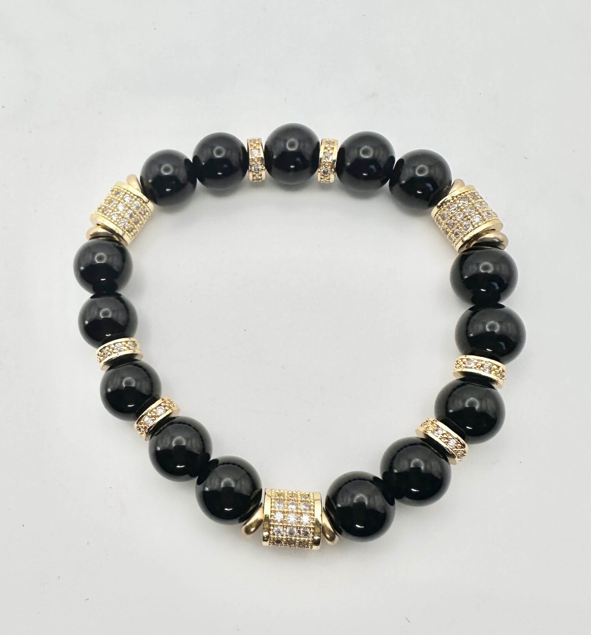 Elegant black beaded bracelet with gold accents and a central decorative bead.